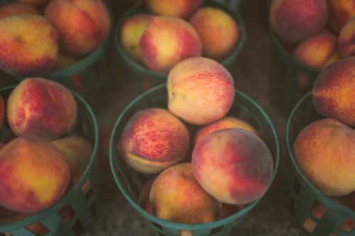 Baskets filled with ripe, colorful peaches arranged neatly at a market.