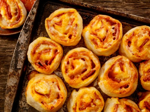 A tray of golden-brown cheese and ham rolls, freshly baked and arranged neatly.