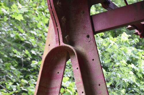 Close-up of a rusted metal structure against a backdrop of green foliage.