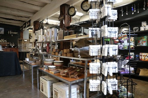 A cozy shop interior featuring shelves of home goods, decor items, and kitchenware, with a warm, inviting atmosphere.