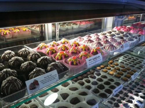 A display case filled with various colorful chocolates and confections, including pink and chocolate-covered treats.
