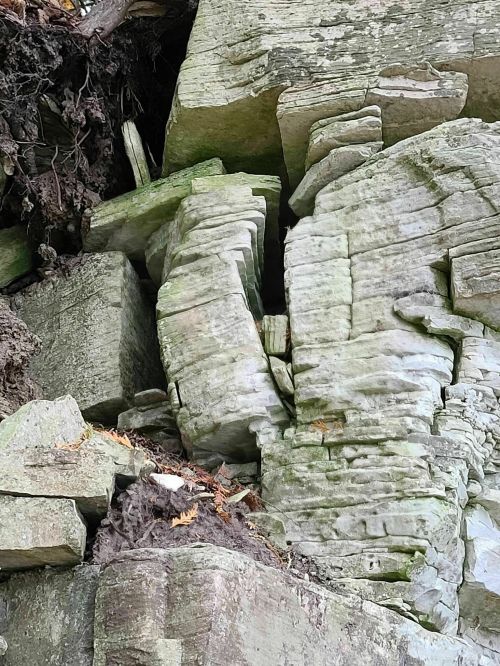 Close-up of layered, weathered rock formations with moss and soil, showcasing natural textures and shapes.