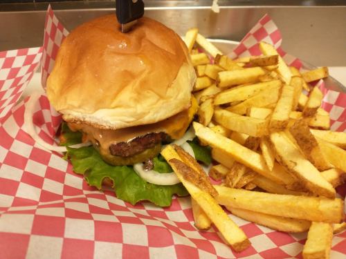 A juicy cheeseburger with lettuce and onion, served with a side of golden French fries on a red-checkered plate.