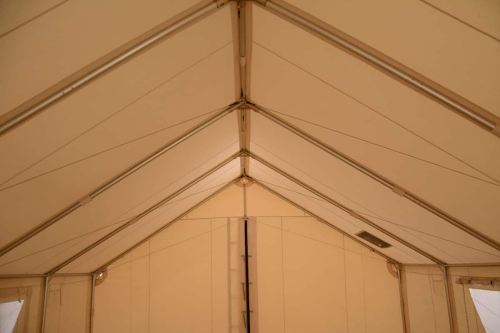 Interior view of a tent, showing the ceiling structure with triangular peaks and metal supports.