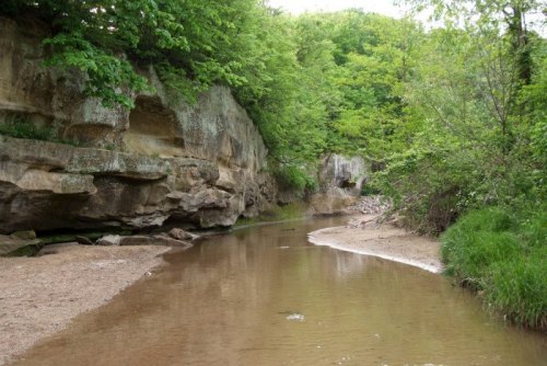 A serene river winding through lush greenery and rocky cliffs, reflecting the surrounding nature.