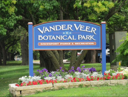 Sign for Vander Veer Botanical Park, featuring colorful flowers and greenery, located in Davenport Parks & Recreation.