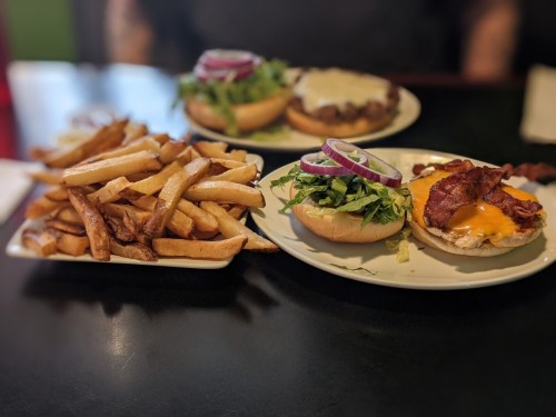 A plate with two burgers topped with lettuce, onions, and cheese, alongside a serving of golden fries.