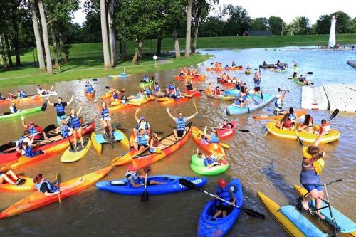 A vibrant scene of people kayaking in a flooded area, with colorful kayaks and participants enjoying the water.