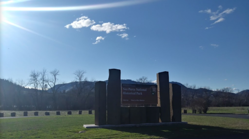 Sign for Nez Perce National Historical Park with mountains and blue sky in the background.