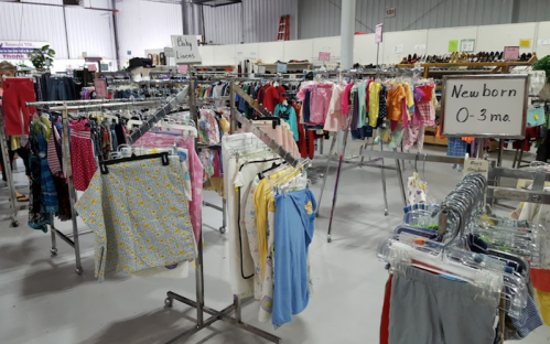 Clothing racks in a store displaying various children's clothes, including newborn and 0-3 months sections.