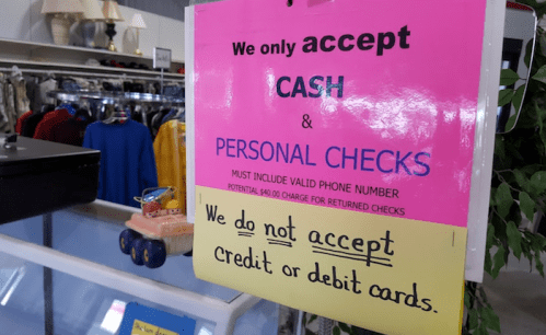 Bright sign stating "We only accept CASH & PERSONAL CHECKS" with a note about not accepting credit or debit cards.
