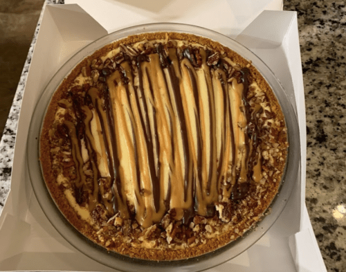 A delicious pie with a graham cracker crust, topped with caramel and chocolate drizzles, and sprinkled with nuts.