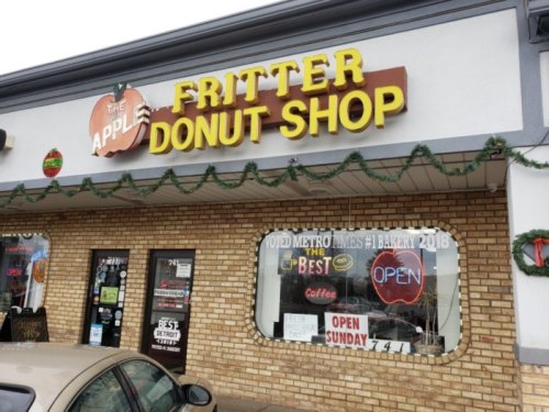 Sign for "The Apple Fritter Donut Shop" with festive decorations and an "Open" sign in the window.
