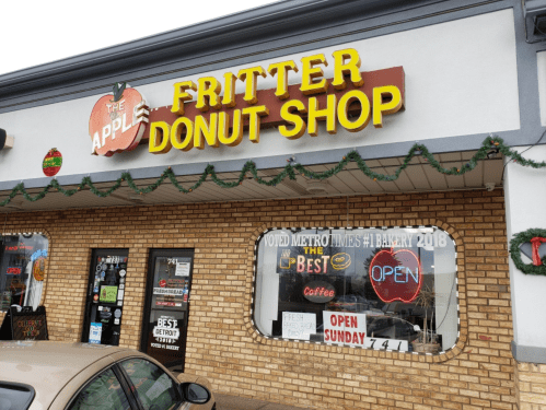 Signage for "The Apple Fritter Donut Shop" with festive decorations and an "Open" sign in the window.