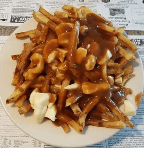 A plate of poutine featuring fries topped with cheese curds and gravy.