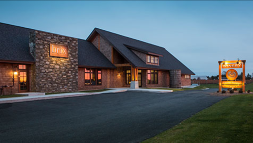Exterior of Brix Winery at dusk, featuring stone architecture and a welcoming sign.