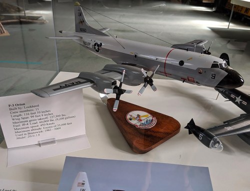 Model of a P-3 Orion aircraft on a wooden display, showcasing specifications and details about its design and capabilities.