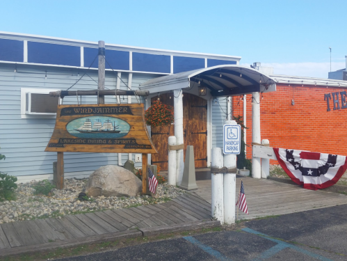 Entrance to The Wind Jammer restaurant, featuring a wooden sign, accessible parking, and patriotic decorations.