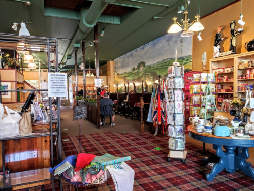 A cozy shop interior with shelves of items, a checkered floor, and customers seated in the background.
