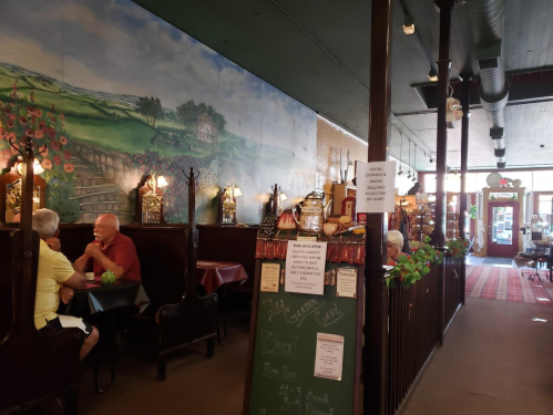 Cozy café interior with mural, wooden booths, and patrons enjoying their meals. Warm, inviting atmosphere.