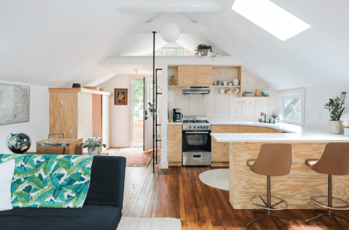Bright, modern kitchen and living area with wooden accents, a sofa, and large windows for natural light.