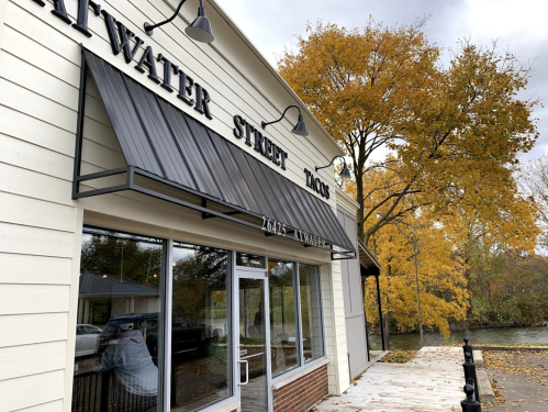 Exterior of a building with an awning that reads "Alwater Street" and autumn trees in the background.