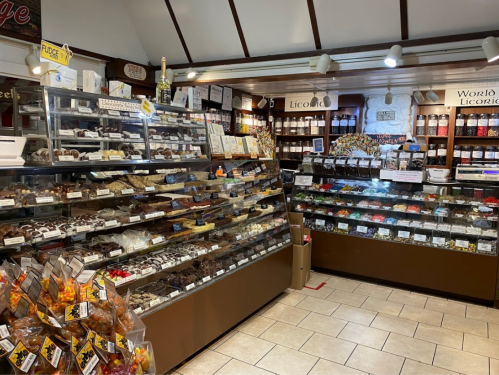 A cozy candy shop filled with various sweets, chocolates, and licorice displayed in glass cases.