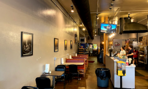 Interior of a casual restaurant featuring booths, a counter, and framed artwork on the walls.