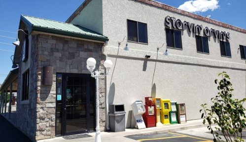 Exterior of a building labeled "Starvin Arvin's" with newspaper stands and a decorative lamp post in front.