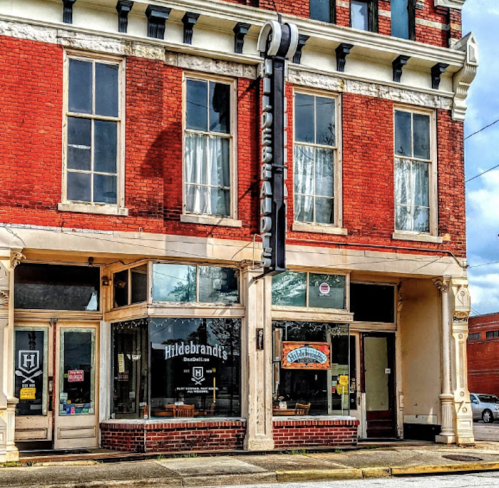 Historic brick building with large windows and a sign reading "Hildebrand's" above a bookstore entrance.