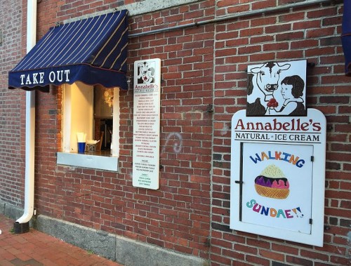 A brick building with a takeout window and a colorful sign for Annabelle's Natural Ice Cream featuring a sundae.