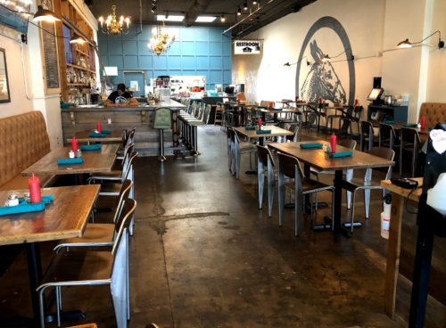 Interior of a restaurant featuring wooden tables, metal chairs, and a mural of a horse on the wall.