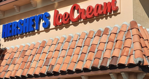 Sign for Hershey's Ice Cream in blue and red letters above a terracotta tiled roof.