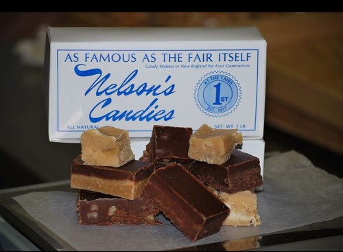 A box of Nelson's Candies with assorted chocolate and fudge pieces stacked in front, showcasing a sweet treat display.