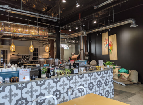 A modern café interior featuring a patterned counter, pendant lights, and artwork on the walls.