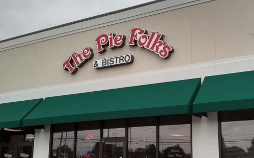 Sign for "The Pie Folks & Bistro" on a storefront with green awnings and a cloudy sky above.