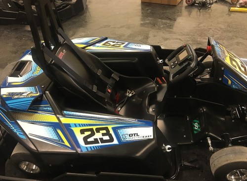 A blue and yellow go-kart with the number 23, featuring a sleek design and a digital dashboard.