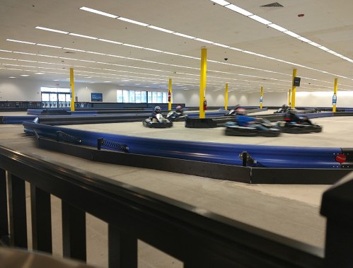 Go-karts racing on an indoor track with yellow pillars and a spacious layout.