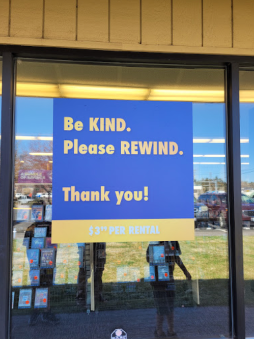 Sign on a store window reads: "Be KIND. Please REWIND. Thank you! $3 per rental."