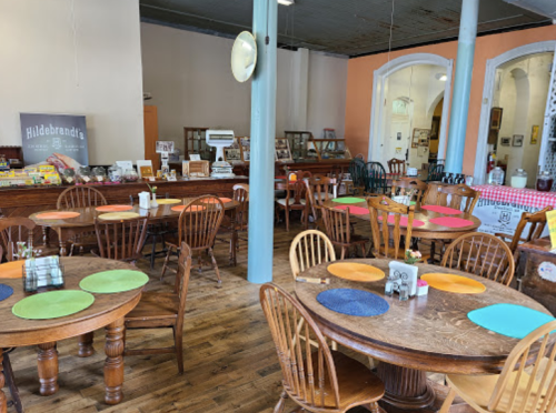 A cozy restaurant interior with wooden tables, colorful placemats, and a vintage decor style.