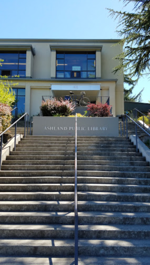 Stairs leading up to the Ashland Public Library, featuring a modern building and greenery.