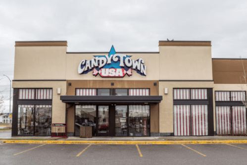 Exterior of a candy store named "Candy Town USA," featuring a colorful sign and large windows.