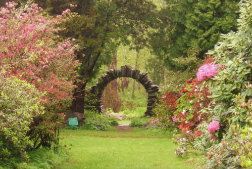 A stone archway surrounded by vibrant flowers and lush greenery in a serene garden setting.