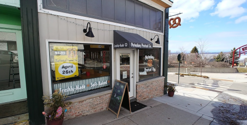 Exterior of a bakery with a sign for National Pretzel Day, featuring a pretzel hanging above the entrance.