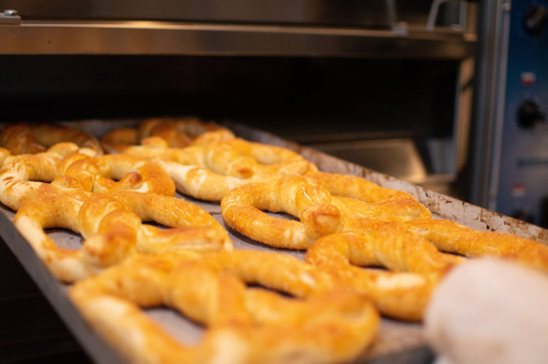 A close-up of freshly baked bread rolls on a tray, with a warm, golden-brown color.