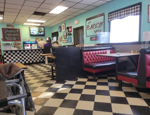 A cozy diner interior with red booths, checkered floor, and a counter in the background. Brightly lit and inviting atmosphere.