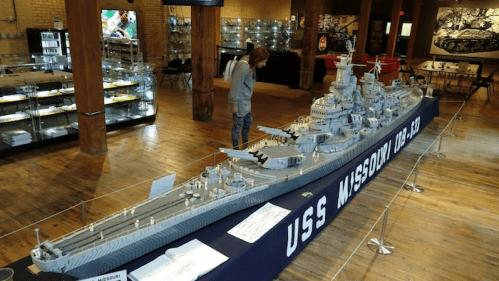 A person examines a large model of the USS Missouri battleship displayed in a museum setting.