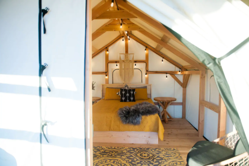 Cozy interior of a glamping tent featuring a bed, wooden accents, and warm lighting.
