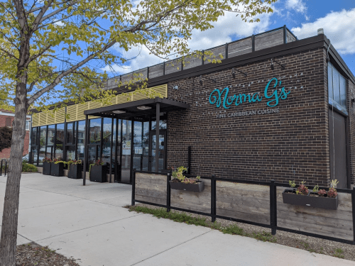 Exterior of Norma G's restaurant, featuring a modern design, large windows, and planters along the sidewalk.