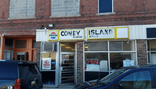 Exterior of Coney Island restaurant with a "OPEN" sign, featuring a Pepsi logo and a brick facade.